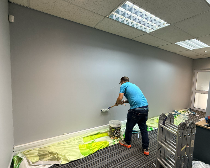 Professional installer preparing and applying seamless fabric wallpaper in a Cape Town office reception.