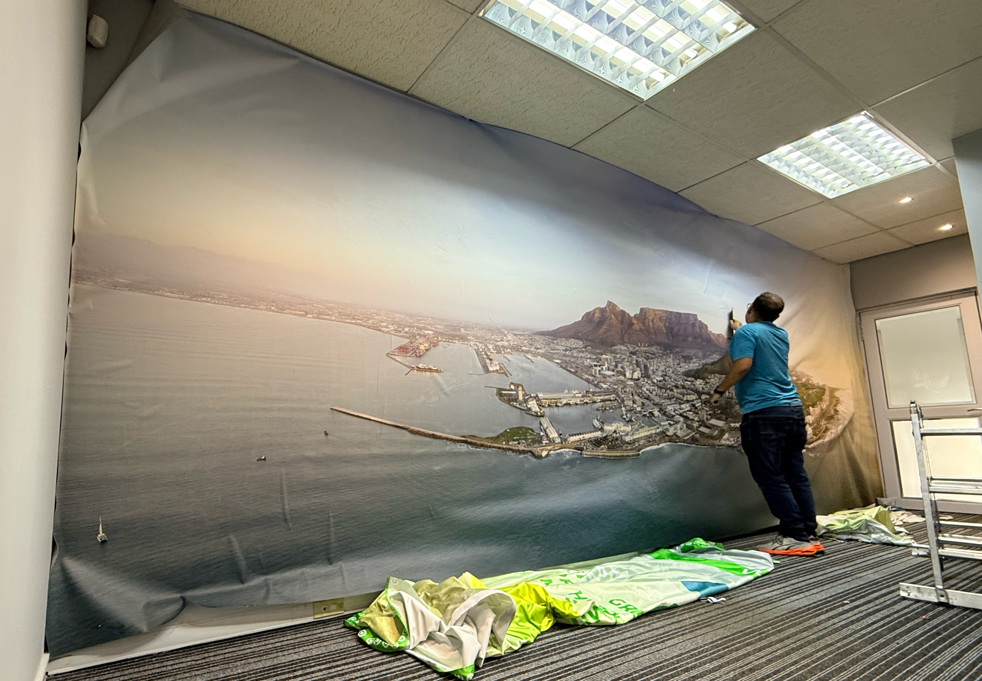 Installer applying seamless custom wallpaper to a commercial office feature wall in Cape Town.